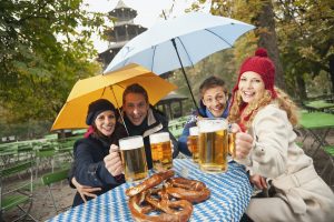 Germany, Bavaria, English Garden, Four persons sitting in rainy beer garden