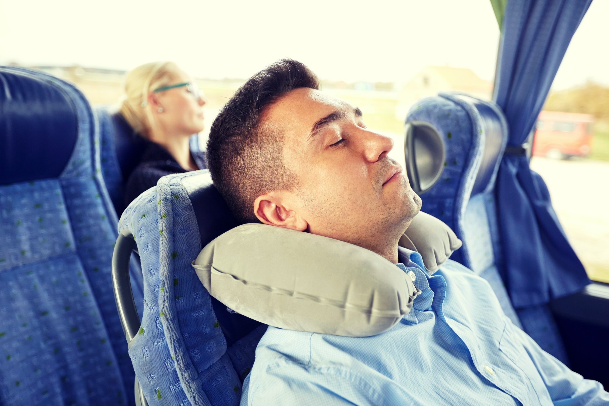 man sleeping in travel bus with cervical pillow